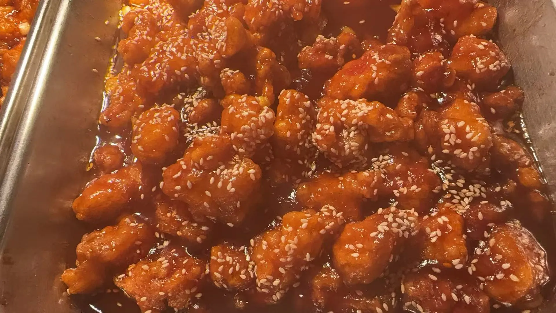 Honey sesame chicken chunks coated in glossy sweet sauce on metal tray at Sakura Buffet Restaurant in Pittsfield